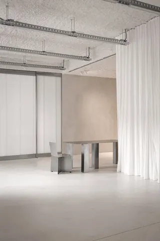 Showroom zone at Holographik Space, Zagreb: table and chair by the curtain