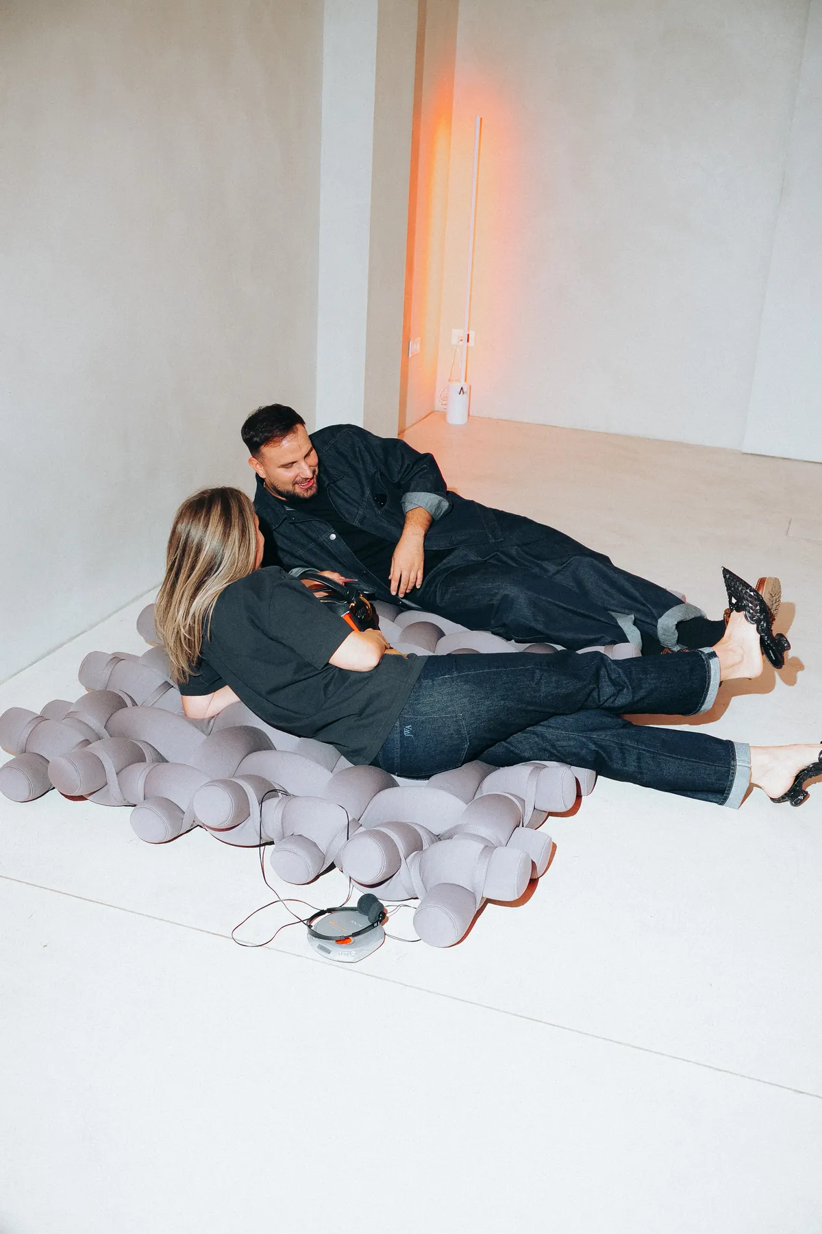 Two guests lying on the Nodo rug with the CD player