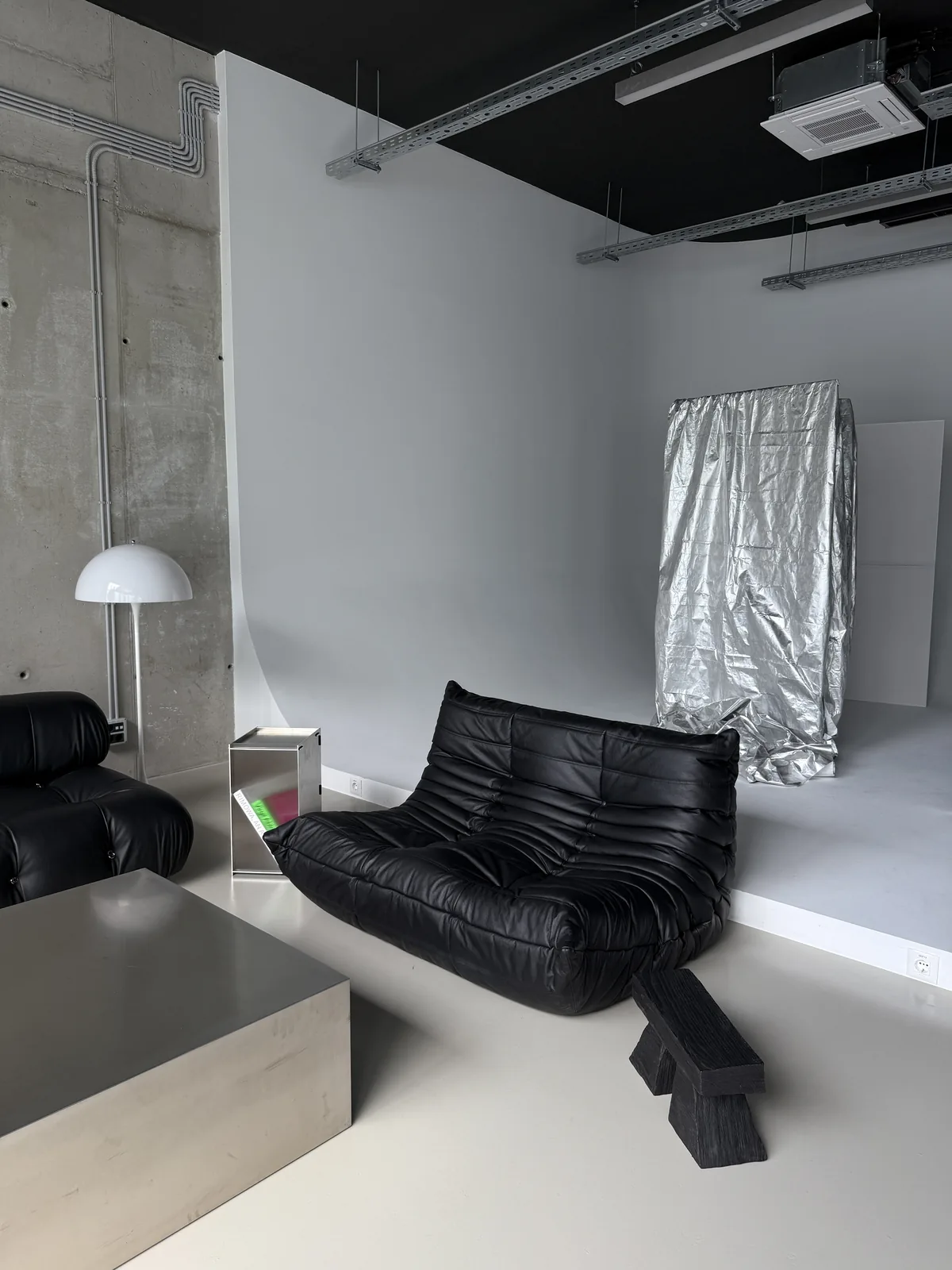 Black leather Togo sofa and a stainless steel plinth in the studio