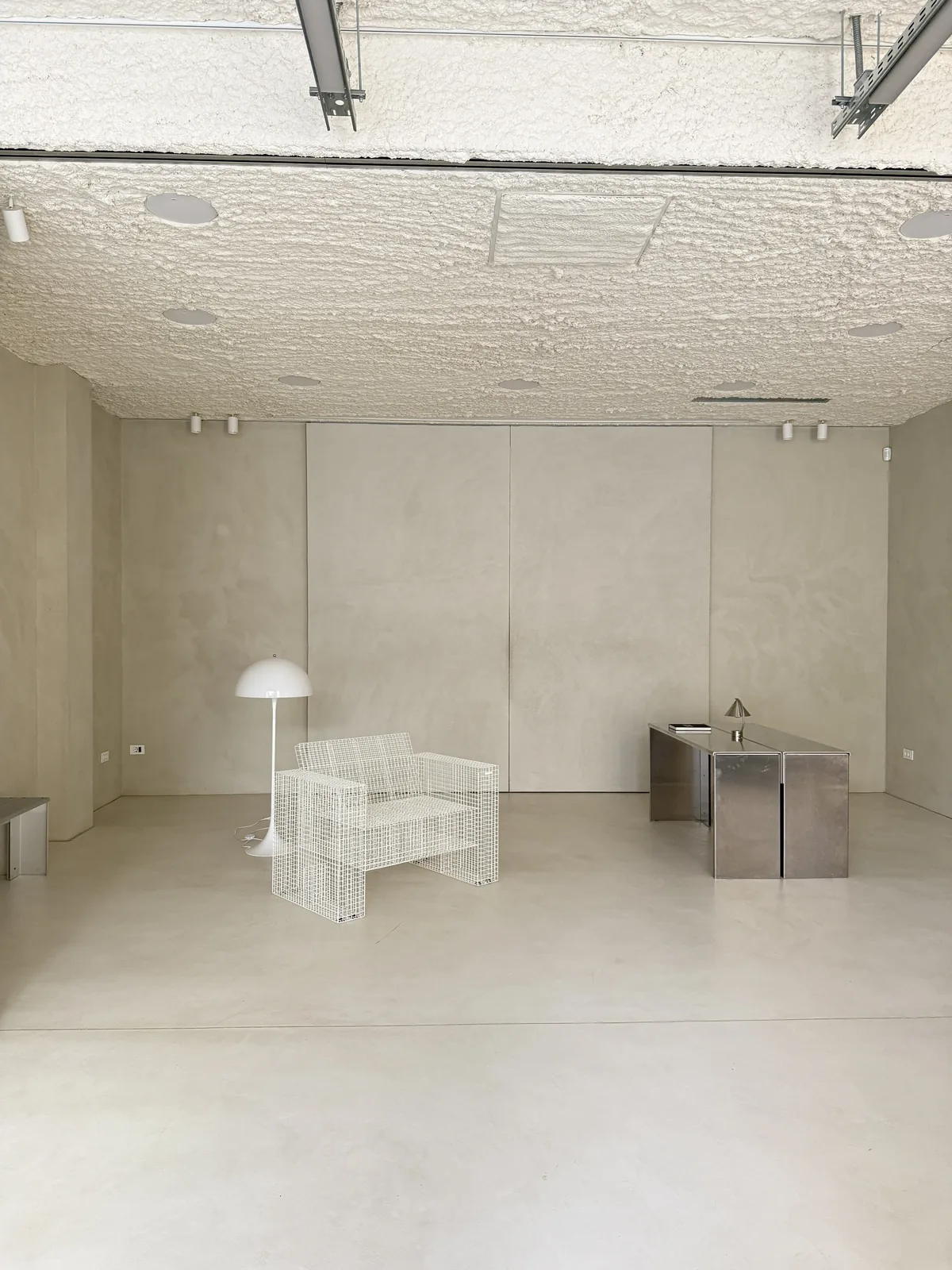 Wire chairs and a stainless steel cube in the white studio