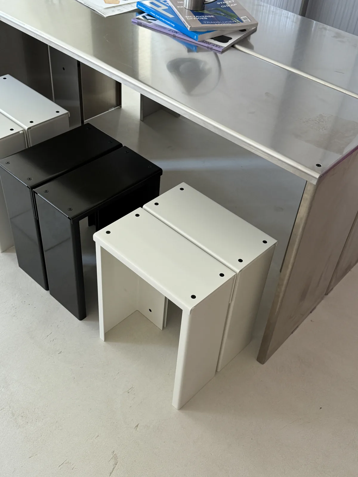 Stainless steel desk with black and white stools