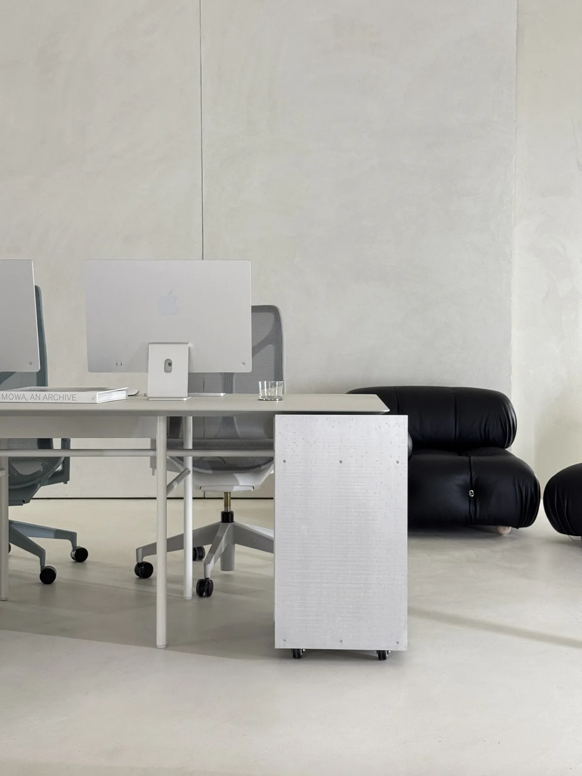 A desk with a steel cube and a mesh chair