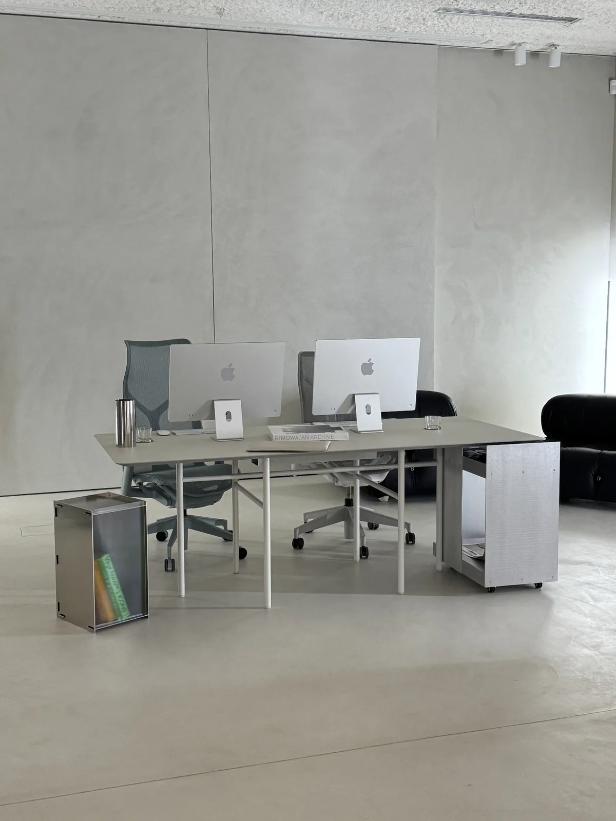 Two desks with iMacs and a steel cube
