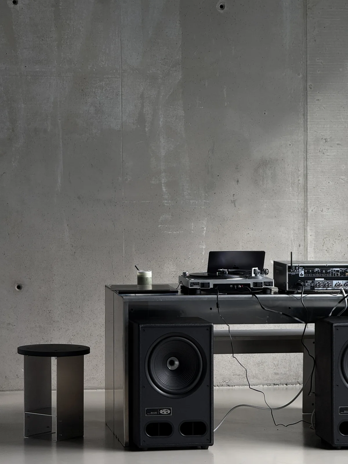 Turntable and speakers on a black console against concrete